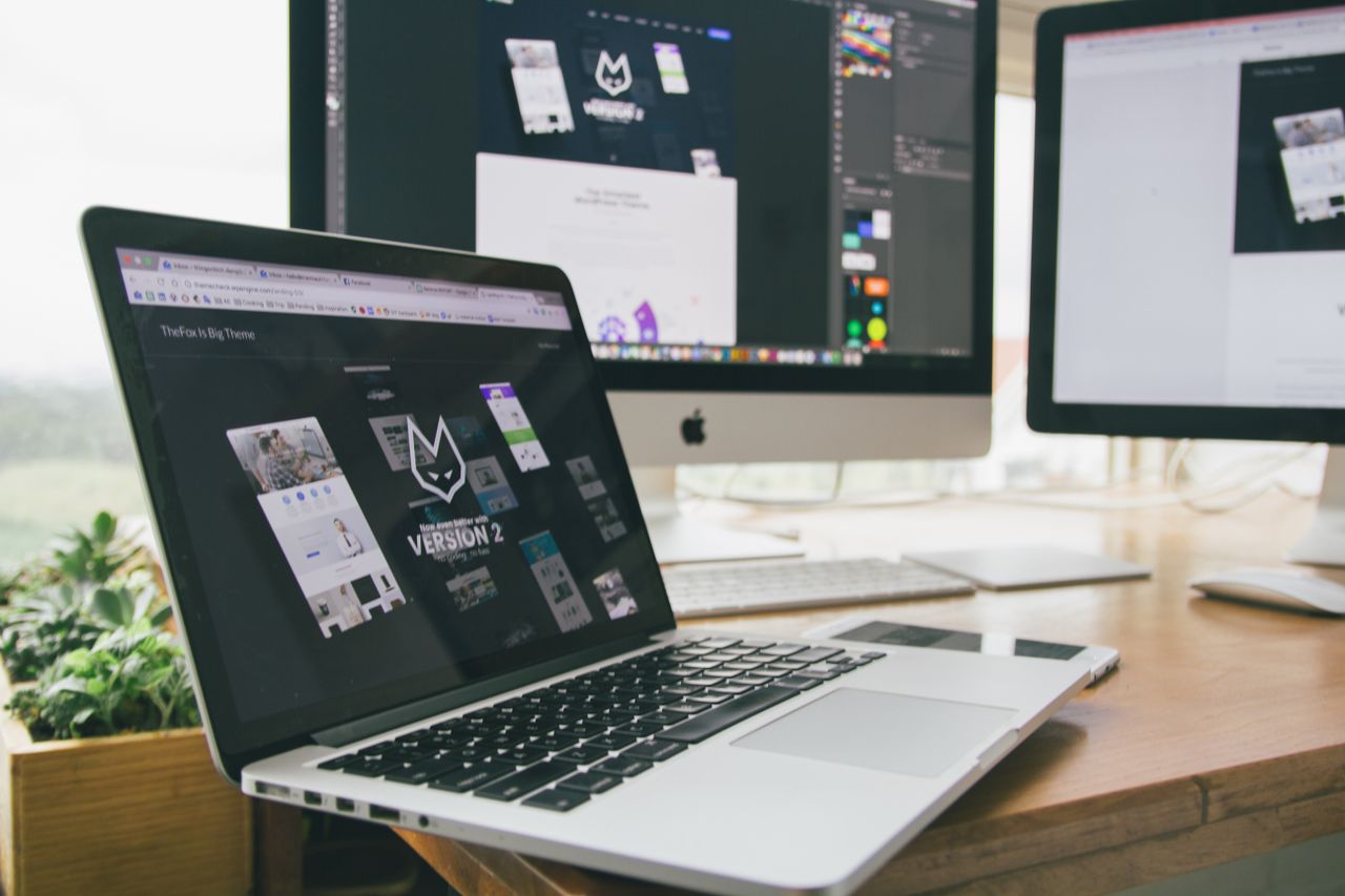 A chic workspace with a laptop and monitors showing design software.