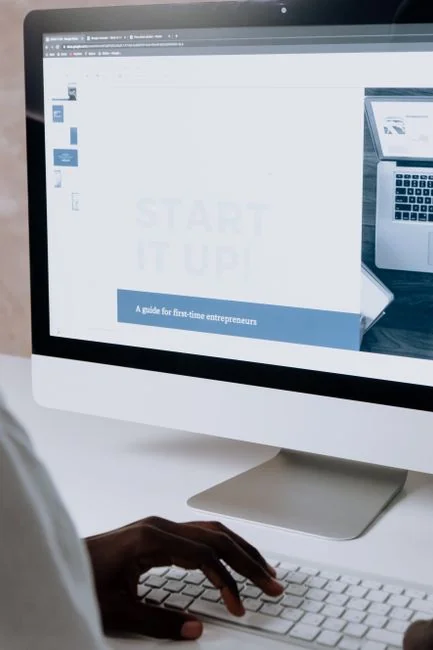 Business professional using a tablet and laptop with a hot drink, focusing on digital content review.